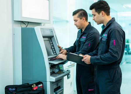 Two ATM service technicians inspecting a cash machine in a Singapore commercial facility